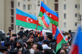 Люди на улице в Баку с флагами Азербайджана