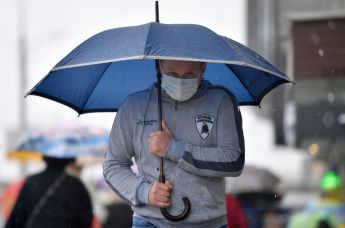 Мужчина в медицинской маске под зонтом