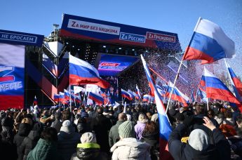 Люди смотрят трансляцию митинга-концерта, посвященного воссоединению Крыма с Россией, у большой спортивной арены "Лужники" в Москве, 18 марта 2022