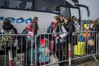 Украинские беженцы ждут посадки в автобус после пересечения границы Украины с Польшей, 30 марта 2022