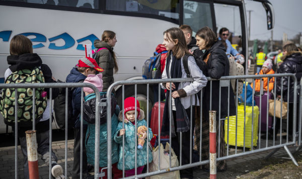 Украинские беженцы ждут посадки в автобус после пересечения границы Украины с Польшей, 30 марта 2022