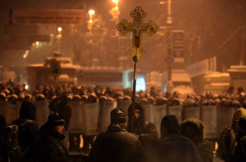 Украинский оппозиционер держит крест перед ОМОНом в центре Киева, 22 января 2014 года