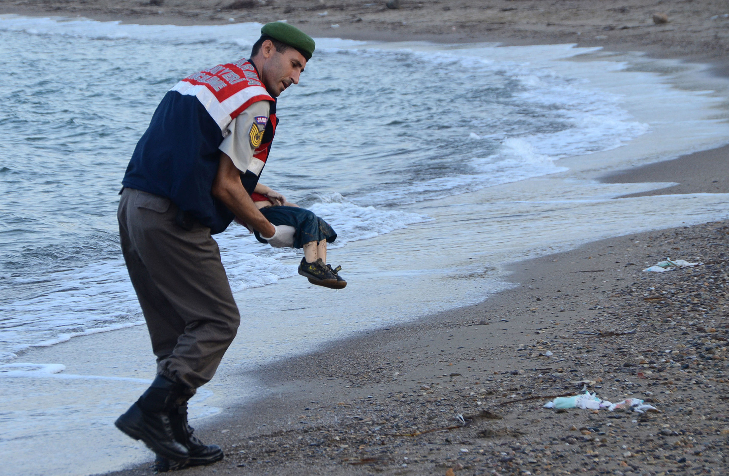 Сотрудник полиции несет тело 3-летнего Айлана Курди, который утонул вместе с матерью и пятилетним братом, пытаясь сбежать из захваченного "ИГ" города. Тело мальчика нашли на берегу Средиземного моря, 2 сентября 2015