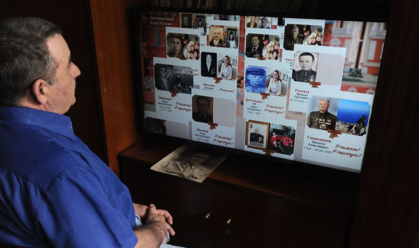 Мужчина смотрит онлайн-трансляцию акции "Бессмертный полк" 