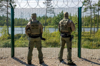 Эстонские полицейские у забора на границе Эстонии и России