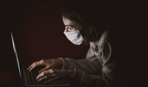 Девушка в маске за ноутбуком