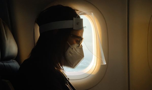 Девушка в респираторе в салоне самолета