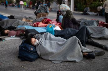 Беженцы и мигранты спят на дороге после пожара в лагере Мориа на острове Лесбос
