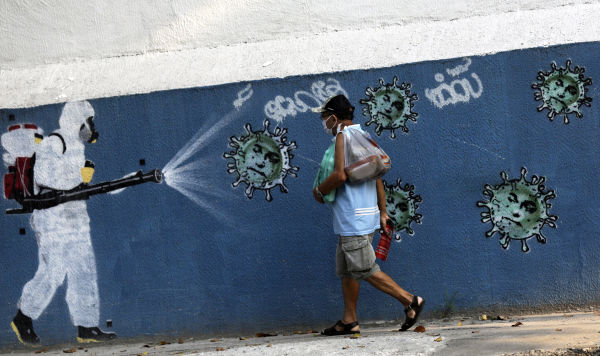 Мужчина проходит мимо граффити, изображающем борьбу с коронавирусом