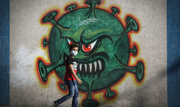 Мальчик проходит мимо граффити с изображением коронавируса Covid-19