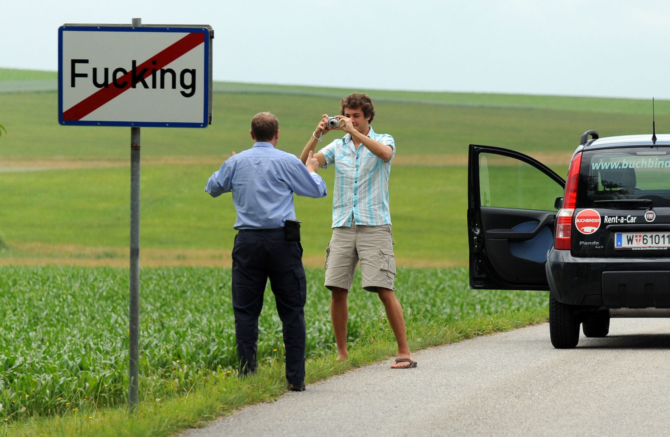 Туристы фотографируются у дорожного знака на выезде из деревни Фуккинг в Австрии