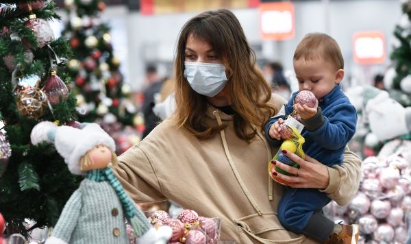 Женщина в защитной маске с ребенком в отделе новогодней атрибутики магазина