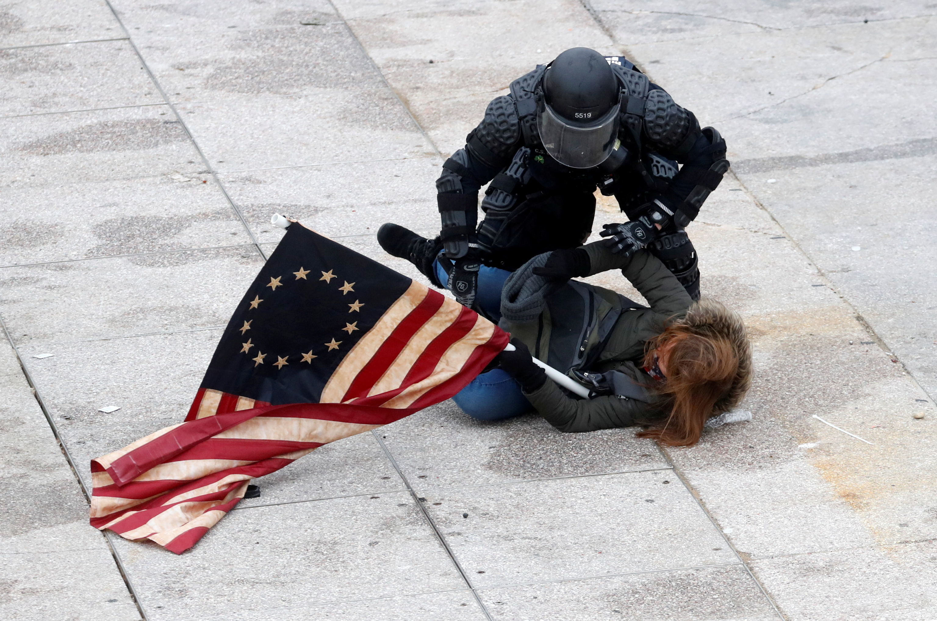 Офицер полиции задерживает сторонника Трампа во время митинга против утверждения Конгрессом США итогов президентских выборов 2020 года 