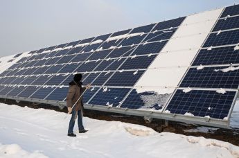 Сотрудник очищает снег с солнечных панелей на  солнечной электростанции