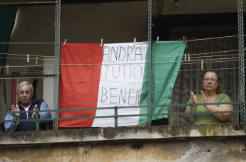Coppia di anziani sul balcone con la bandiera dell'Italia con la scritta "Andrà tutto bene" a Roma