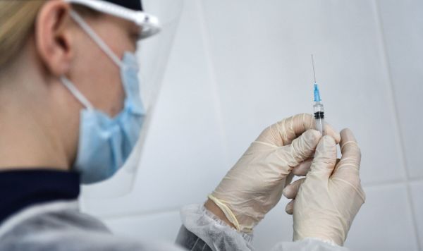 Медицинский работник держит шприц с вакциной