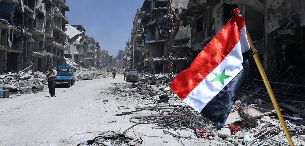 Флаг Сирии в освобожденном лагере палестинских беженцев "Ярмук" на юге Дамаска