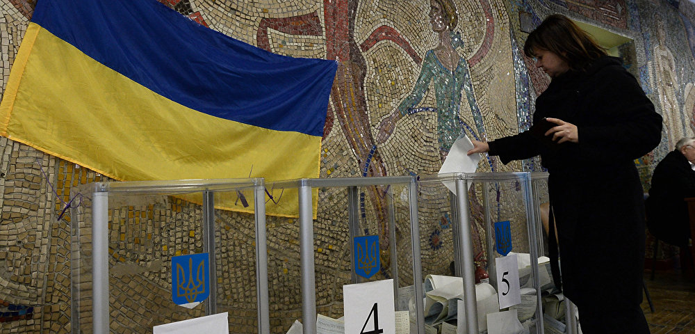 Женщина опускает бюллетени в урну для голосования на одном из избирательных участков в Киеве. Архивное фото