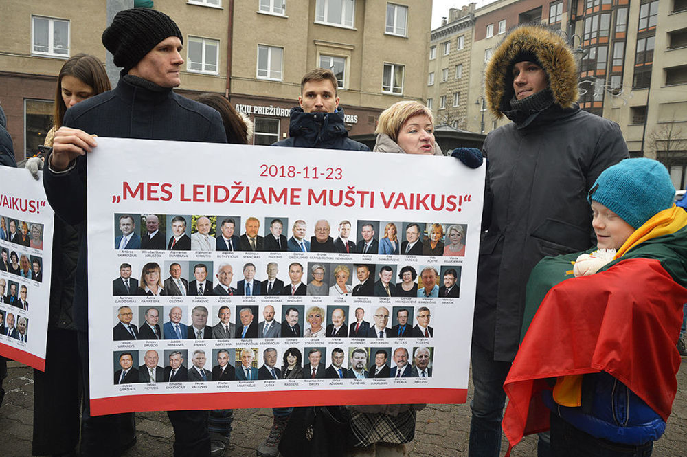 Участники митинга с плакатом с фотографиями  депутатов, инициировавших поправки к закону о ювенальной юстиции, Вильнюс, 25 ноября 2018